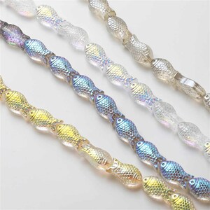May include: A strand of iridescent glass fish beads in four colors: gold, blue, purple, and clear. The beads are strung on a clear thread and are all facing the same direction.