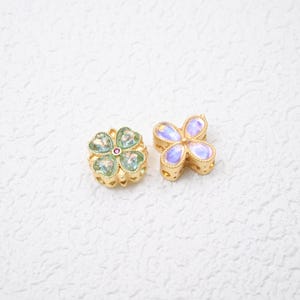 Contas espaçadoras em formato de flor, banhadas a ouro 18K, com pedra olho de gato e zircônia cúbica.