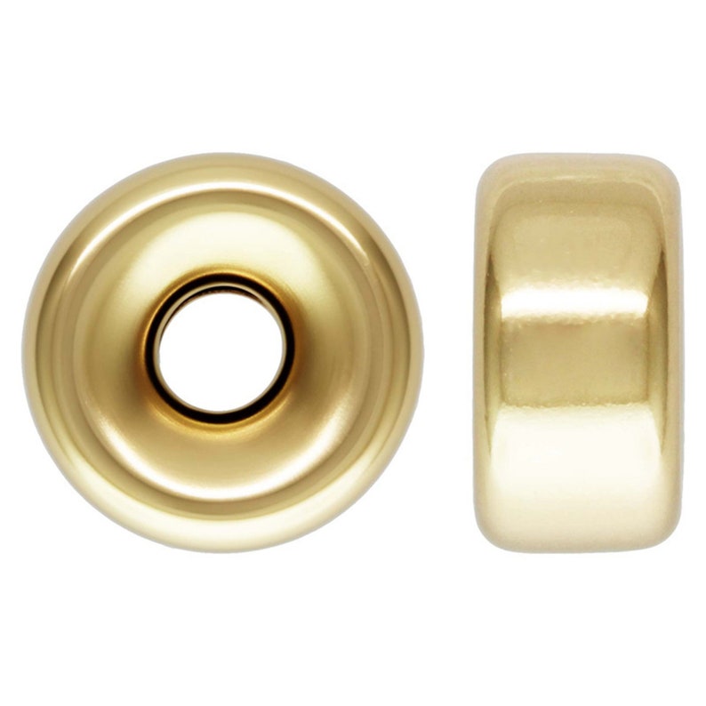 May include: Two gold-toned metal bead spacers. The spacer on the left has a raised center ring. The spacer on the right is a solid cylinder.