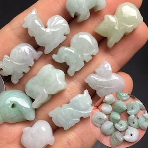 May include: A collection of small, carved jade animal figurines in various shapes, including a rooster, squirrel, and bear. The figurines are primarily pale green and white, with smooth, polished surfaces. A smaller group of similar figurines is in a circular inset.