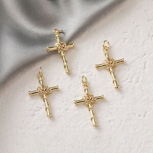 May include: Four gold-tone metal cross charms with a rose design. Each cross has a loop at the top for attaching to a necklace or bracelet.