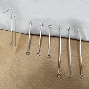 May include: A set of silver-toned metal jewelry components consisting of one pair of long drop earrings with hook wires and six individual straight metal bars, each featuring a small circular loop at both the top and bottom ends for connecting.