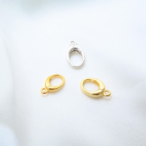May include: Three oval jewellery clasps. Two are gold-coloured, and one is silver. Each clasp has a small loop for attaching to jewellery. The clasps are on a white background.