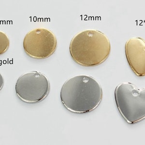 Pode incluir: Uma coleção de berloques de metal dourado e prateado em várias formas e tamanhos. Os berloques incluem discos redondos nos tamanhos 8 mm, 10 mm e 12 mm, e uma forma de coração de 12x12 mm. O texto "KC plated gold" e "rhodium" são visíveis.
