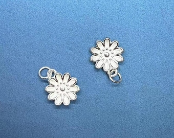 May include: Two silver-toned flower charms with white enamel. Each charm has a loop for attaching to a necklace or bracelet.