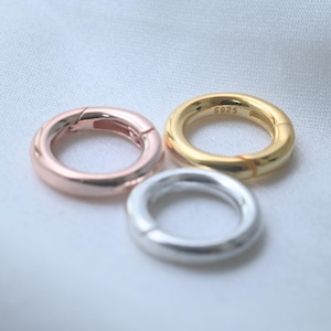 Può includere: Tre chiusure rotonde in oro rosa, oro e argento. La chiusura dorata ha stampato "S925". Queste chiusure circolari hanno un'apertura a cerniera per il fissaggio ai gioielli. Le chiusure sono su sfondo bianco.