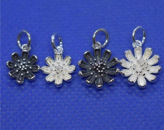 May include: Four silver flower charms, two with black enamel and two with white enamel.