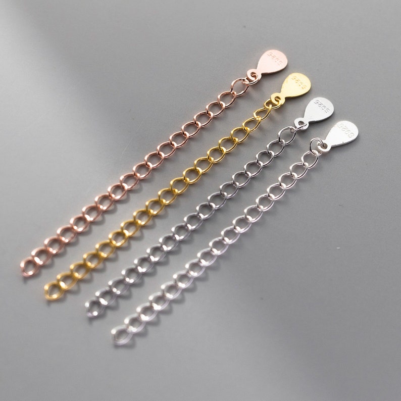 May include: Four silver chain extenders in different colors: rose gold, gold, silver, and white gold. Each extender has a small tag with the word "925" on it.