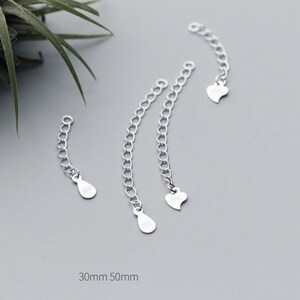May include: Three silver extender chains with different end pieces. The chains are 30mm and 50mm long. The end pieces are a teardrop, a heart, and another teardrop.