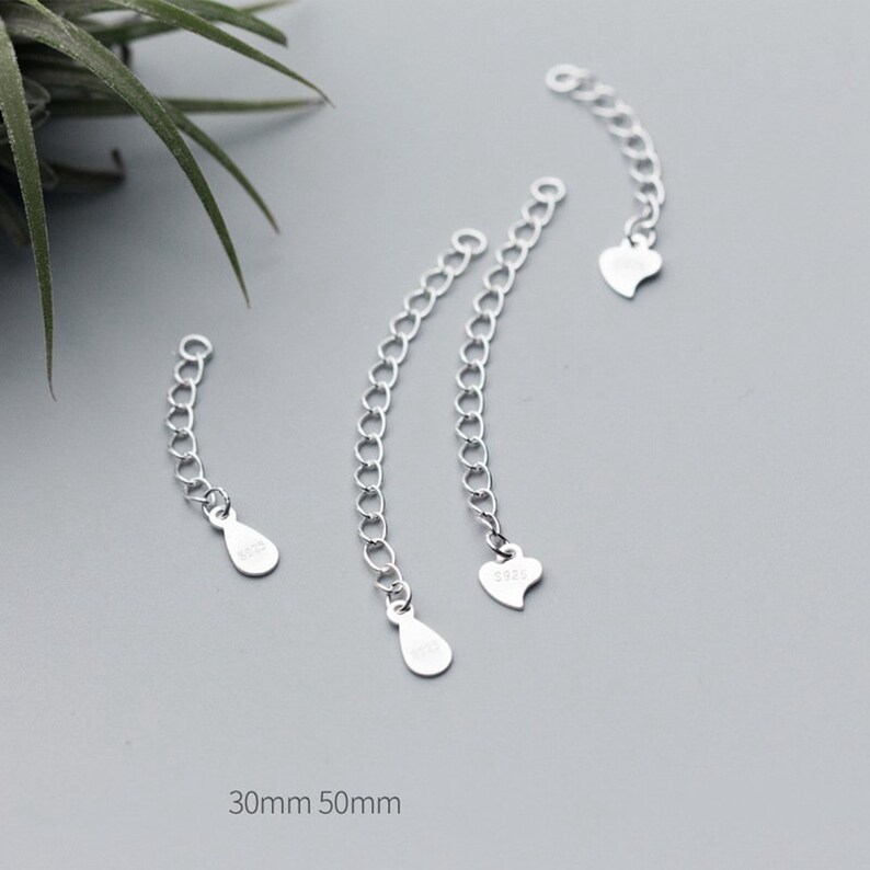 May include: Three silver extender chains with different end pieces. The chains are 30mm and 50mm long. The end pieces are a teardrop, a heart, and another teardrop.