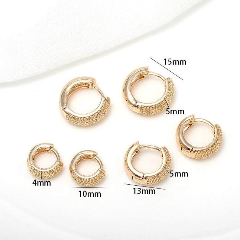 Puede incluir: Pendientes de aro dorados en varios tama&ntilde;os, cada uno con una banda de peque&ntilde;as piedras brillantes. Se proporcionan las medidas: 4 mm, 10 mm, 13 mm y 15 mm de di&aacute;metro, con un ancho de 5 mm. Estos pendientes ofrecen una opci&oacute;n de joyer&iacute;a cl&aacute;sica y elegante.