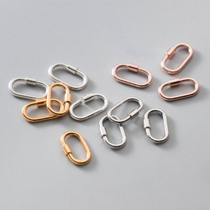 Op de afbeelding: Assortiment van ovale metalen sluitingen in zilver, goud en rosé goud. De sluitingen zijn klein en hebben een gladde, gepolijste afwerking.