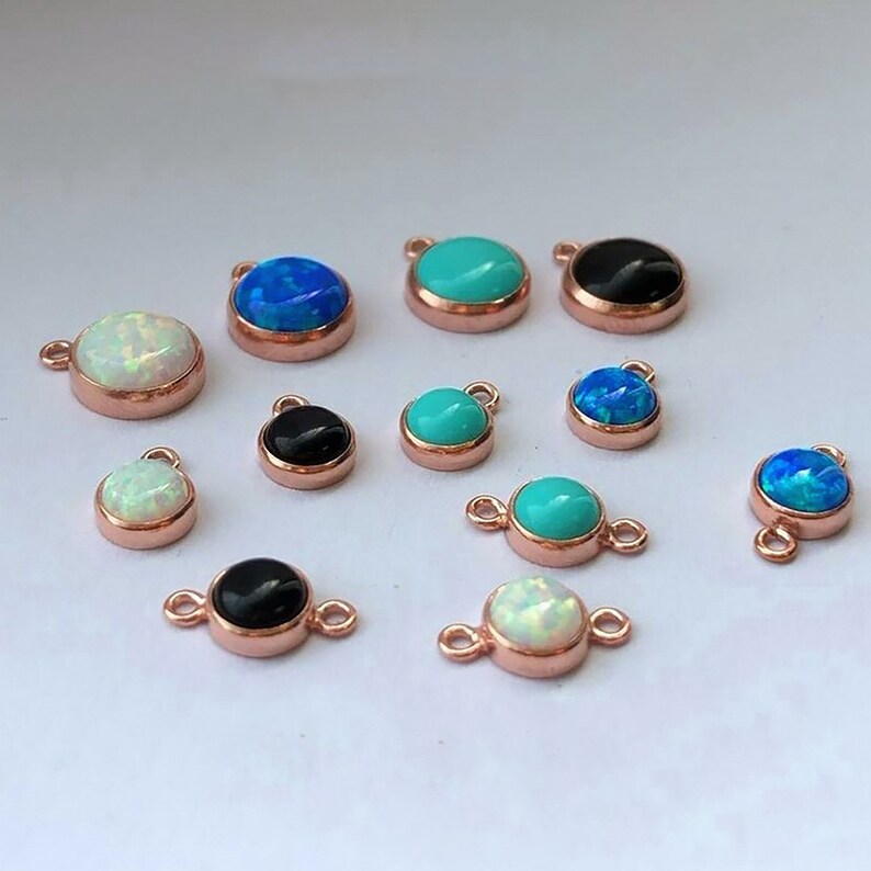 May include: Assortment of 12 rose gold plated charms with various gemstone colors, including turquoise, opal, and blue. Each charm features a round gemstone cabochon.