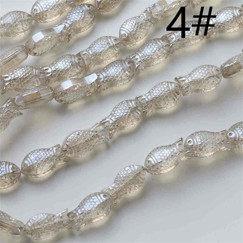 May include: A strand of translucent, light brown, glass fish-shaped beads. The beads are strung on a clear thread. The image shows a close-up of the beads, with the text "4#" visible in the background.