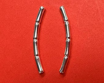May include: A pair of silver earrings with a curved, segmented design. Each earring is made of multiple small, cylindrical beads connected together.