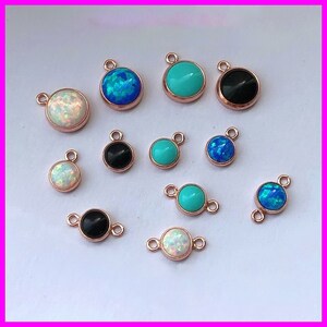 May include: Assortment of 12 rose gold plated pendant charms with various gemstone colors, including turquoise, opal, and black. Each charm features a round gemstone cabochon.