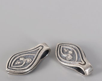 May include: Two silver-toned metal pendant charms with a teardrop shape and an intricate floral design.
