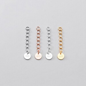 May include: Four silver chain extenders with a round tag at the end. Each tag is stamped with "S925" and the chains are silver, rose gold, gold, and silver.