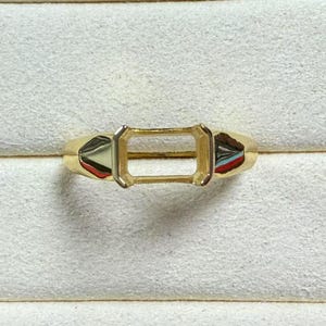 Könnte beinhalten: Eine goldene Ringfassung mit einem leeren rechteckigen Platz für einen Edelstein.
