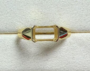 May include: A gold ring setting with an empty rectangular space for a gemstone.