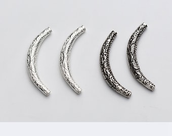 May include: Four silver-toned metal beads with an ornate design. The beads are curved and have a decorative pattern.