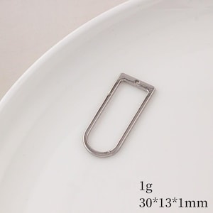 May include: A silver-colored, rectangular pendant with rounded edges and a small hole at the top. The pendant measures 30mm x 13mm x 1mm and weighs 1g. The pendant is displayed on a white surface.