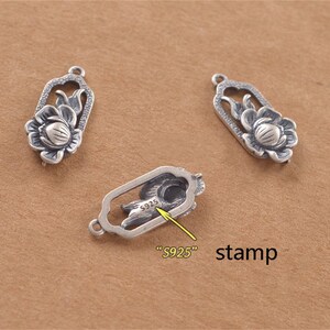May include: Three silver charms featuring a lotus flower design. The charm on the right has a stamp that reads "S925".