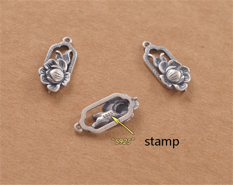 May include: Three silver charms featuring a lotus flower design. The charm on the right has a stamp that reads "S925".