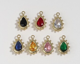 May include: Seven teardrop-shaped charms with gold-colored settings and colorful gemstones. The gemstones are black, red, clear, blue, orange, pink, and green. Each charm has a small loop at the top for attaching to jewelry.
