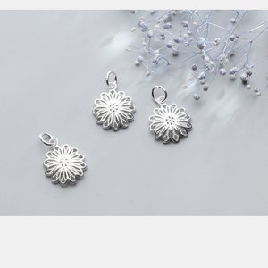 May include: Three silver filigree flower charms with a delicate, intricate design. The charms are perfect for adding a touch of elegance to jewelry projects.