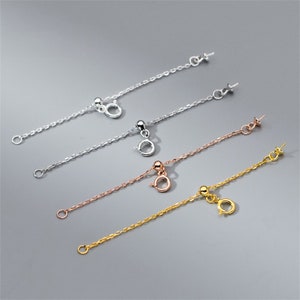 May include: Four silver, gold, and rose gold chain extenders with a jump ring and a bead at one end and a lobster clasp at the other end.