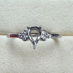 以下が含まれることがあります： バンドに小さなダイヤモンドがついた、洋梨型のセッティングのシルバーリングです。