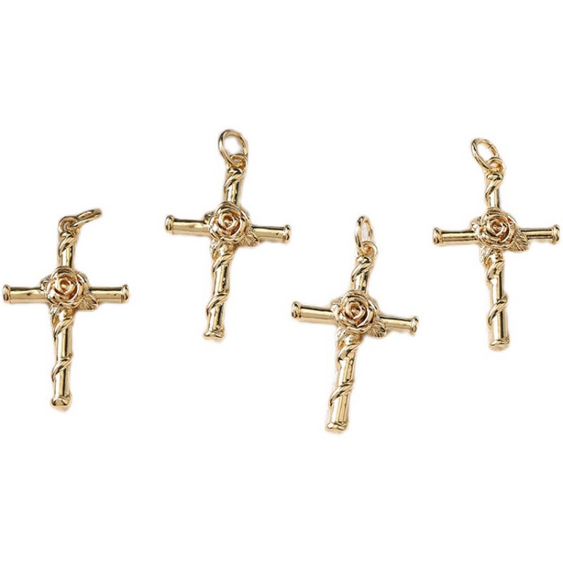 May include: Four gold-tone cross charms with a rose design. Each charm has a loop at the top for attaching to a necklace or bracelet.