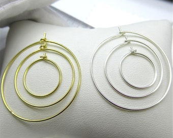Puede incluir: Un par de pendientes de aro con tres círculos concéntricos. Los pendientes están hechos de metal y están disponibles en oro y plata.
