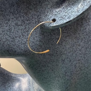 May include: A pair of gold hoop earrings. The earrings are simple and delicate, with a smooth, polished finish.