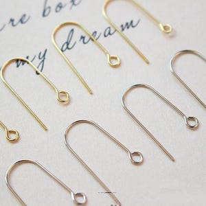 May include: A close-up of a set of gold and silver earring hooks. The hooks are made of metal and have a simple design.