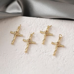 May include: Four gold-tone cross charms with a rose design. The crosses are made of twisted metal and have a rose in the center.