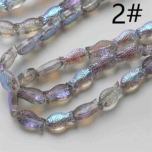 May include: A strand of iridescent glass fish beads. The beads are translucent and have a rainbow sheen. The beads are strung on a clear thread. The image includes the text "2#"