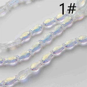 May include: A strand of iridescent glass beads shaped like fish. The beads are strung on a clear thread and have a subtle shimmer. The image includes the number "1#" in the top right corner.