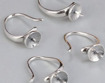 May include: A collection of silver-colored earring findings. Each finding features a curved hook design with a small, cup-shaped setting at the end, designed to hold a bead or other decorative element. The findings are displayed against a light gray background.