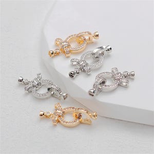 May include: Four silver and gold tone metal clasps with clear crystal embellishments. The clasps are designed to be used as jewelry making supplies.