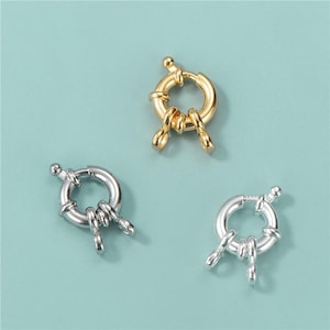 Puede incluir: Tres cierres de metal plateado y dorado con un anillo y tres puntas. Los cierres se utilizan para la fabricación de joyas.