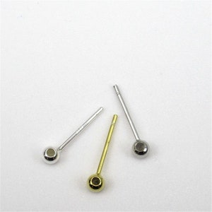 May include: Three earring posts with ball ends. One is silver, one is gold, and one is silver with a larger ball.