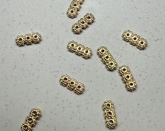 Pode incluir: Um grupo de dez espaçadores de contas de metal dourado. Cada espaçador é feito de quatro círculos conectados com uma superfície texturizada.