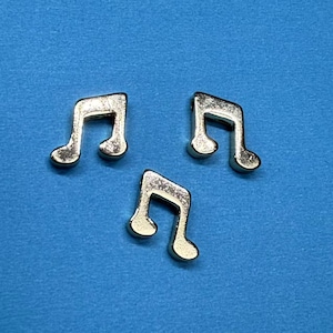 Könnte beinhalten: Drei silberne Musiknoten-Anhänger. Die Anhänger haben die Form einer Musiknote und sind etwa 2,5 cm lang.