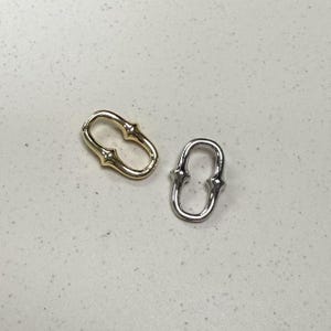 May include: Two metal connector rings, one gold and one silver, with a unique design featuring two loops connected by a small bar.