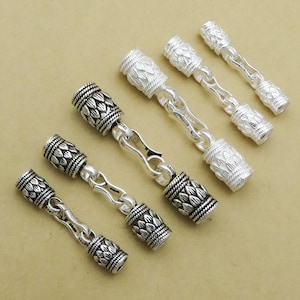 May include: Five silver chain connectors with decorative end caps. The end caps have a textured, leaf-like design.