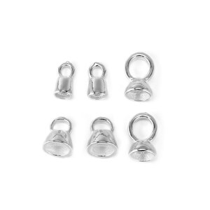 Peut inclure: Un ensemble de six embouts de cordon en métal argenté en forme de cloche, disposés sur deux rangées. Chaque pièce présente une base conique lisse avec une boucle circulaire sur le dessus, conçue pour la bijouterie et la finition de cordons.