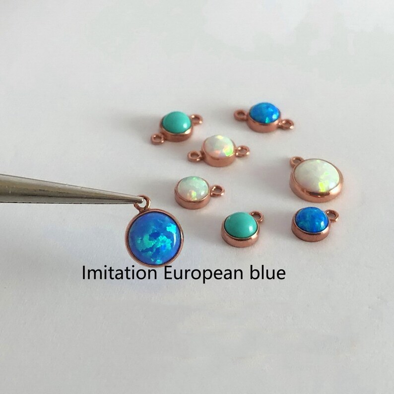 May include: Assortment of small, round, gemstone-like charms in various colors, including blue, turquoise, and white. The charms are attached to small, gold-colored loops. The text "Imitation European blue" is visible below the charms.