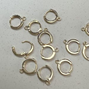 May include: A collection of gold-toned hoop earring findings. The findings are made of metal and have a smooth finish. They are perfect for creating custom earrings.